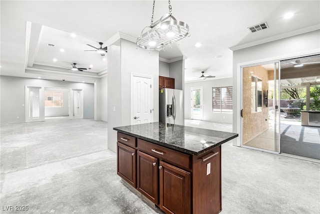 kitchen with decorative light fixtures, a center island, ornamental molding, dark stone counters, and stainless steel fridge