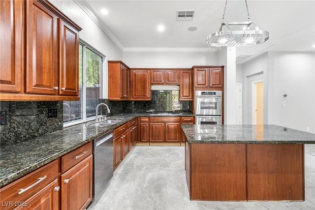 kitchen with sink, stainless steel appliances, decorative light fixtures, and a center island