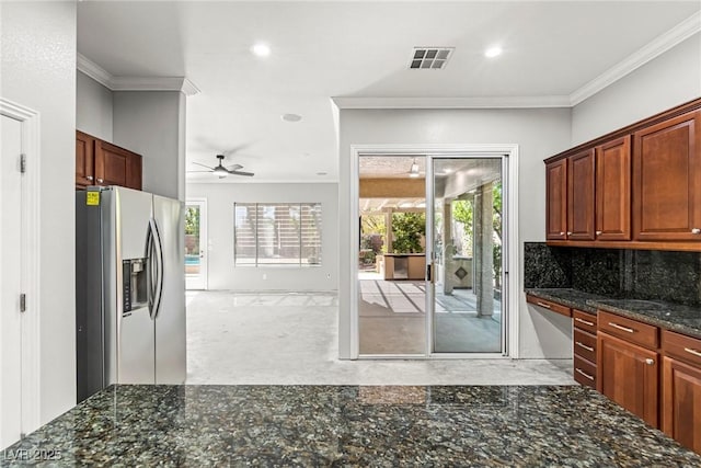 kitchen with dark stone countertops, stainless steel appliances, ceiling fan, ornamental molding, and backsplash