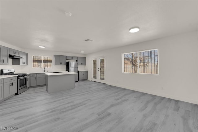 kitchen with appliances with stainless steel finishes, gray cabinetry, light hardwood / wood-style flooring, and a center island