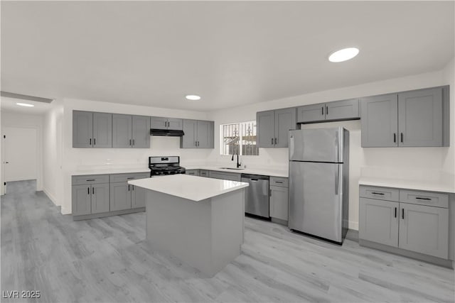 kitchen featuring stainless steel appliances, a center island, sink, and gray cabinets