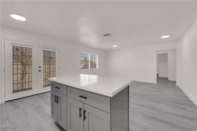 kitchen with gray cabinets, french doors, light hardwood / wood-style floors, and a center island