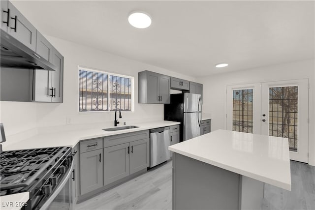 kitchen with sink, french doors, gray cabinets, a kitchen island, and appliances with stainless steel finishes