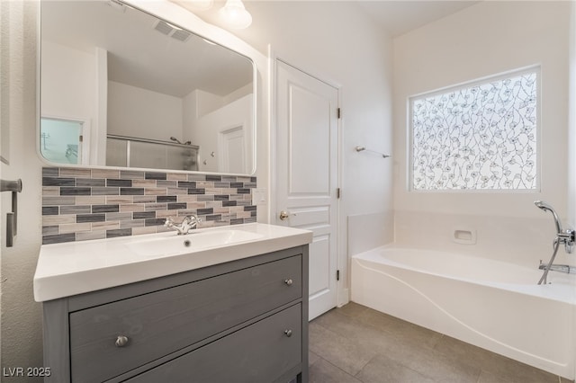 bathroom with a washtub, vanity, decorative backsplash, and tile patterned floors