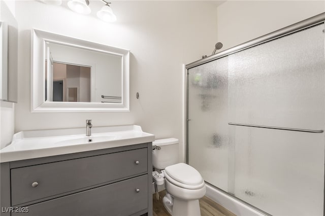 bathroom with a shower with door, vanity, and toilet