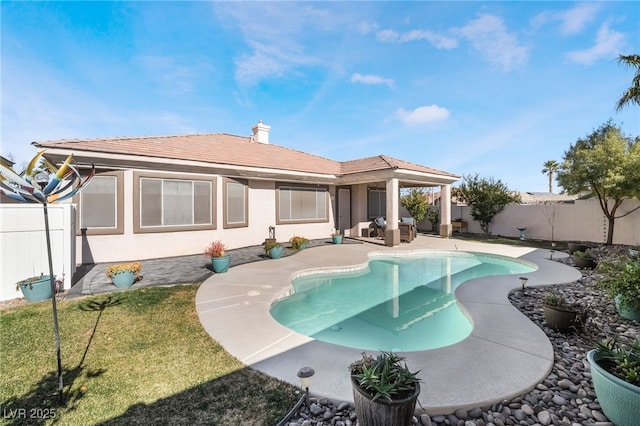 back of property with a lawn and a fenced in pool