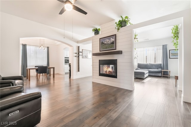 living room featuring ceiling fan with notable chandelier, dark hardwood / wood-style floors, and a fireplace