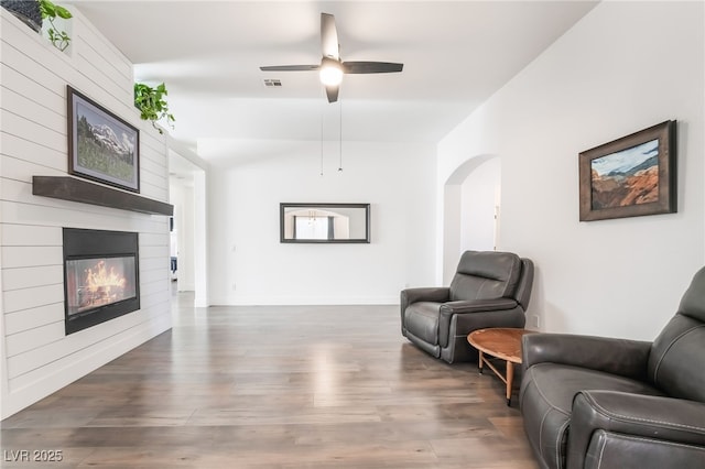 living room with ceiling fan, dark wood-type flooring, and a fireplace