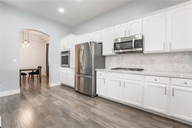 kitchen featuring decorative light fixtures, white cabinetry, hardwood / wood-style floors, tasteful backsplash, and appliances with stainless steel finishes