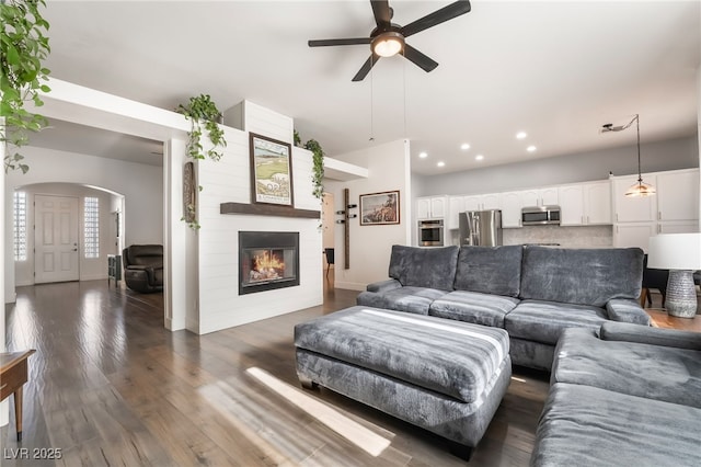 living room with a fireplace, ceiling fan, and dark hardwood / wood-style flooring