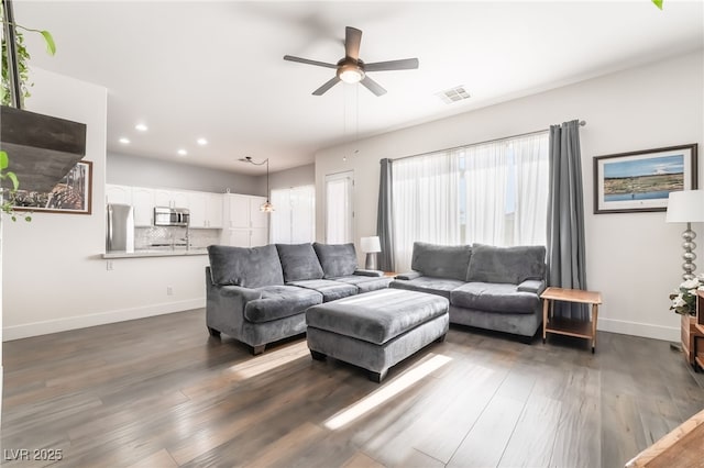 living room featuring ceiling fan and dark wood-type flooring