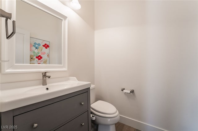 bathroom with toilet, vanity, and hardwood / wood-style flooring