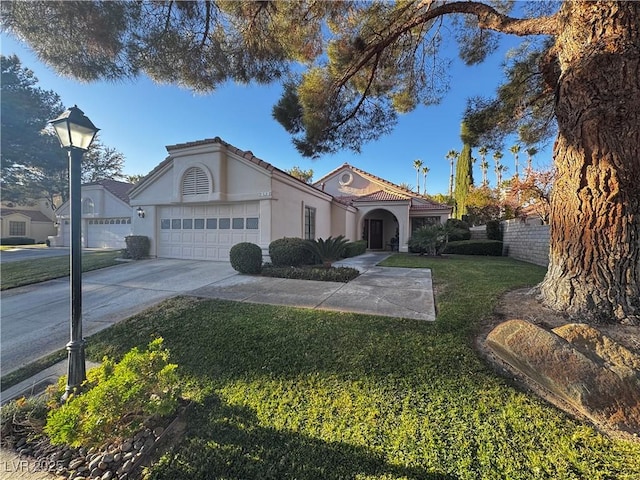 mediterranean / spanish-style home featuring a garage and a front lawn