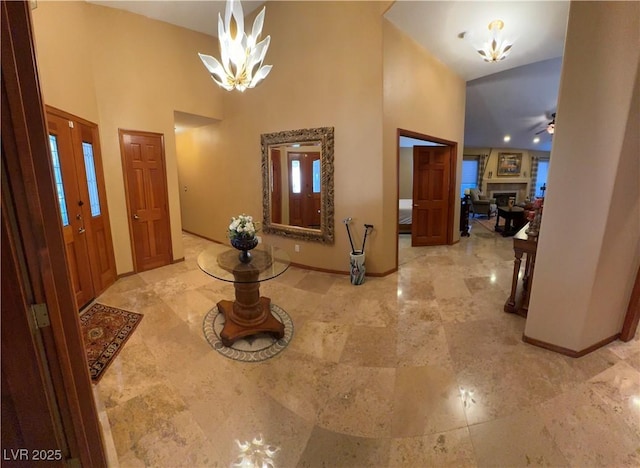 foyer entrance featuring a towering ceiling and ceiling fan with notable chandelier