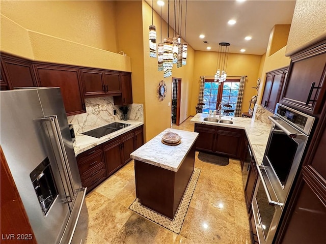 kitchen featuring appliances with stainless steel finishes, kitchen peninsula, sink, decorative light fixtures, and tasteful backsplash