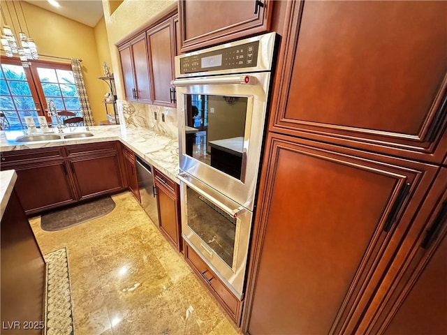 kitchen with decorative light fixtures, tasteful backsplash, an inviting chandelier, appliances with stainless steel finishes, and sink