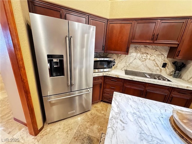 kitchen featuring light stone counters, appliances with stainless steel finishes, and decorative backsplash