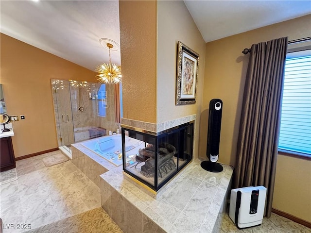 bathroom with shower with separate bathtub, an inviting chandelier, a fireplace, lofted ceiling, and vanity