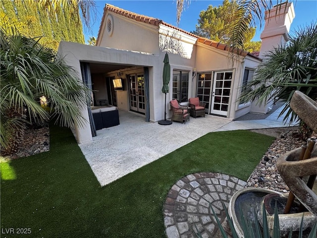 back of house featuring french doors, a patio area, and a yard