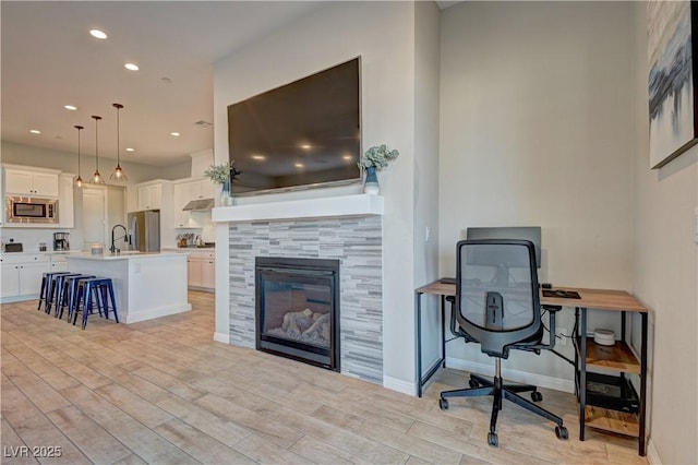 home office featuring sink, light hardwood / wood-style flooring, and a tile fireplace