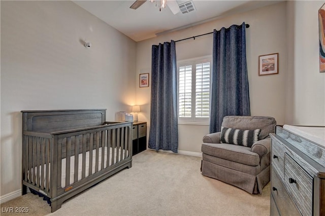 carpeted bedroom with ceiling fan and a crib