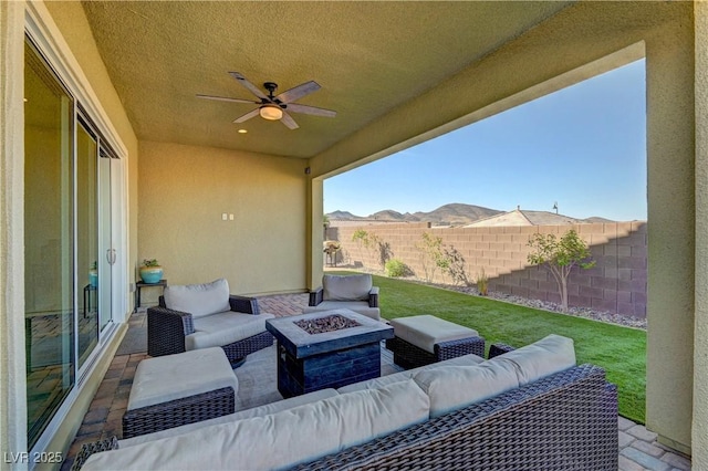 view of patio / terrace featuring an outdoor living space with a fire pit, ceiling fan, and a mountain view