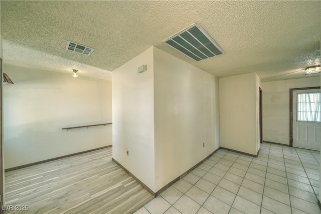 empty room featuring a textured ceiling and light wood-type flooring