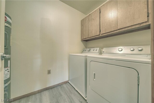 clothes washing area featuring washing machine and clothes dryer, cabinets, and light hardwood / wood-style flooring