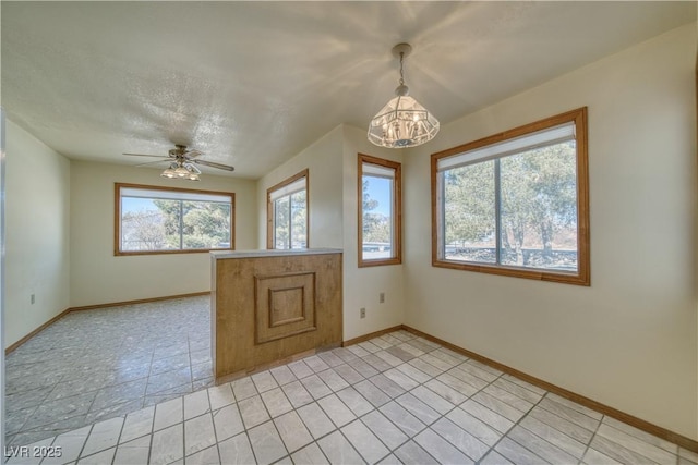 empty room featuring ceiling fan with notable chandelier and a textured ceiling