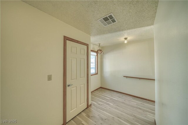 empty room featuring a textured ceiling and light wood-type flooring