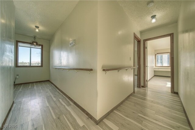 corridor featuring a textured ceiling and light hardwood / wood-style flooring