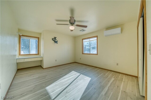 unfurnished bedroom featuring light wood-type flooring, ceiling fan, and a wall mounted air conditioner