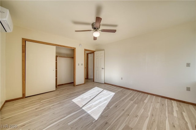 unfurnished bedroom featuring ceiling fan, a wall mounted air conditioner, light hardwood / wood-style floors, and a closet