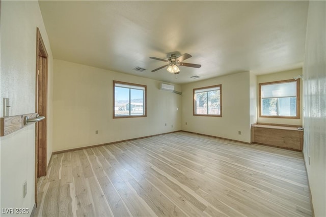 spare room with light hardwood / wood-style flooring, a wall unit AC, and ceiling fan