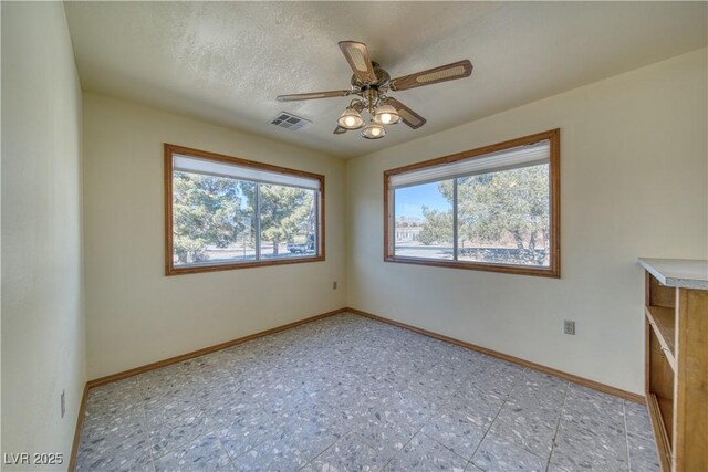 empty room with a textured ceiling and ceiling fan