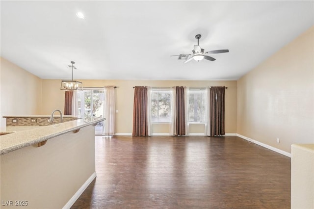 unfurnished living room with ceiling fan with notable chandelier and dark hardwood / wood-style floors