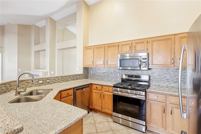 kitchen with stainless steel appliances, sink, kitchen peninsula, backsplash, and light stone countertops