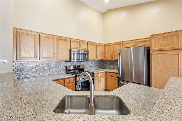 kitchen with light stone countertops, a high ceiling, decorative backsplash, appliances with stainless steel finishes, and sink