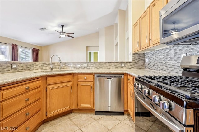 kitchen with light stone countertops, tasteful backsplash, appliances with stainless steel finishes, ceiling fan, and sink