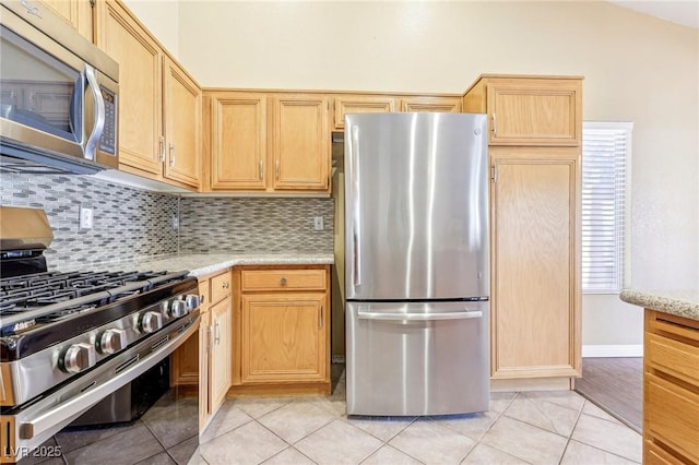 kitchen with stainless steel appliances, light brown cabinetry, light tile patterned floors, and tasteful backsplash