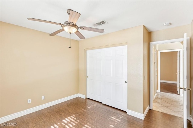 unfurnished bedroom featuring ceiling fan, a closet, and wood-type flooring