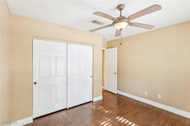 unfurnished bedroom with ceiling fan, dark wood-type flooring, and a closet