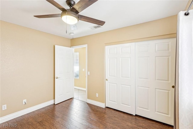 unfurnished bedroom featuring dark wood-type flooring, ceiling fan, and a closet