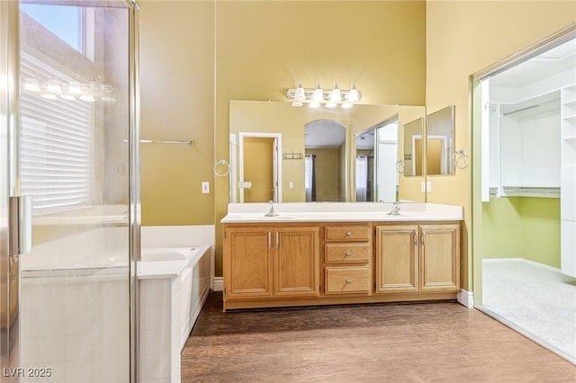 bathroom featuring wood-type flooring, vanity, and plus walk in shower