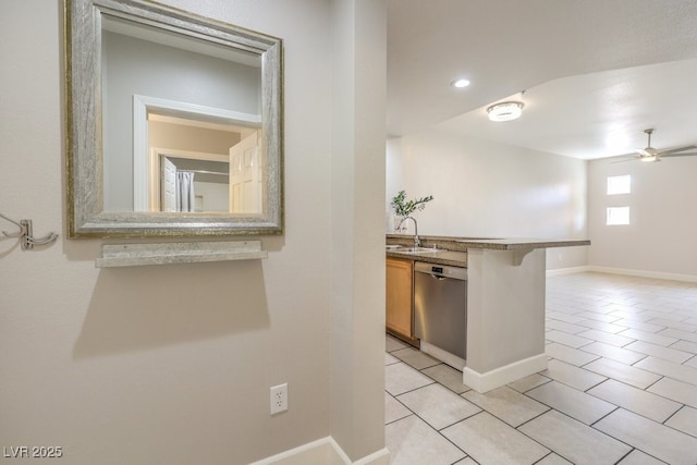 kitchen featuring dishwasher, light tile patterned floors, a kitchen bar, ceiling fan, and sink