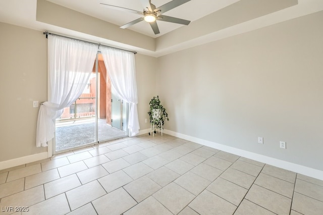 unfurnished room with a raised ceiling, ceiling fan, and light tile patterned floors