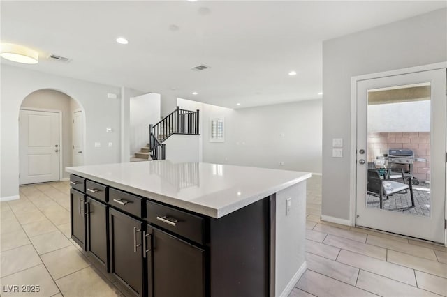 kitchen with light stone counters, a center island, and light tile patterned flooring