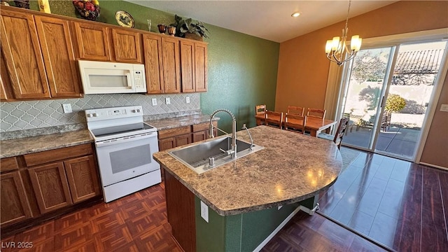 kitchen featuring sink, white appliances, pendant lighting, a chandelier, and a kitchen island with sink