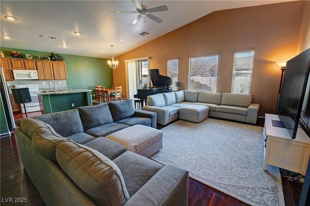 living room with ceiling fan with notable chandelier, vaulted ceiling, and dark wood-type flooring