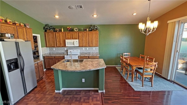 kitchen with white appliances, pendant lighting, lofted ceiling, a kitchen island with sink, and sink